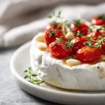 Pyszny pieczony camembert z pomidorkami koktajlowymi i platkami czosnku.