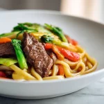 Udon z wołowina i warzywami z air fryer na talerzu.